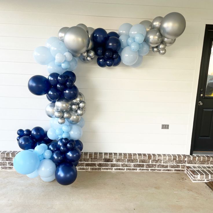 a balloon letter made out of blue, silver and white balloons in front of a door