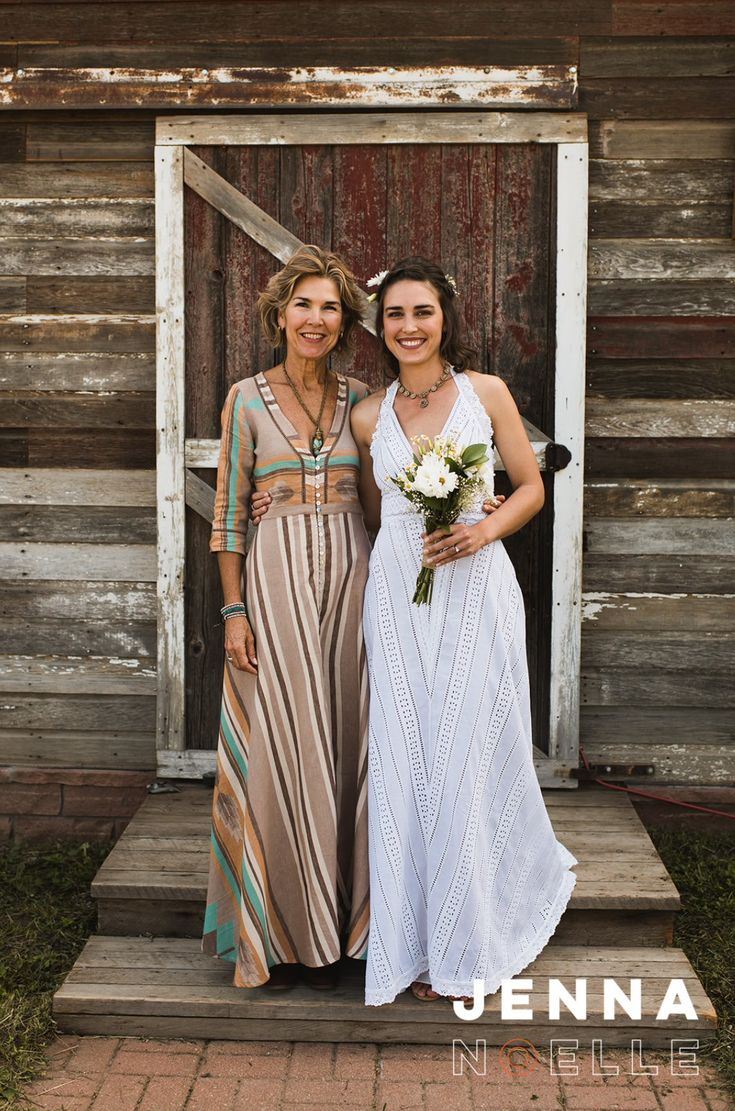 two women standing next to each other in front of a wooden building with an open door