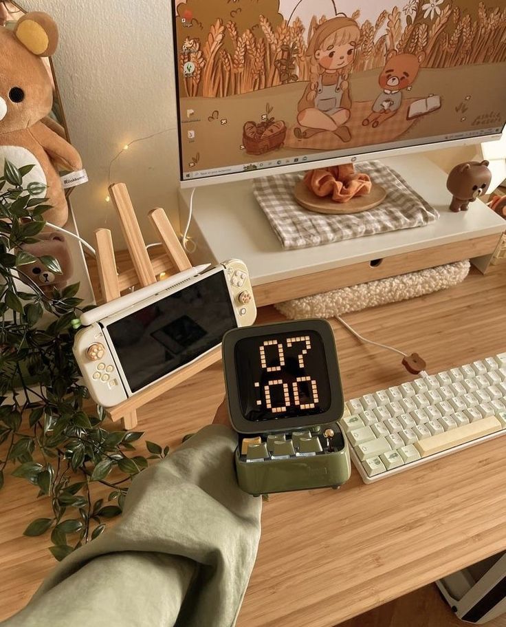 an alarm clock sitting on top of a wooden desk next to a computer monitor and keyboard