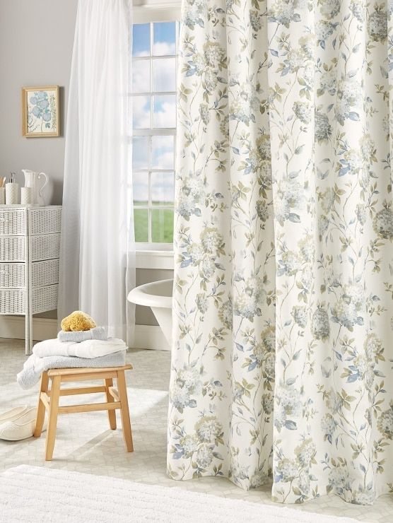 a bathroom with a white bath tub and shower curtain next to a wooden stool in front of a window