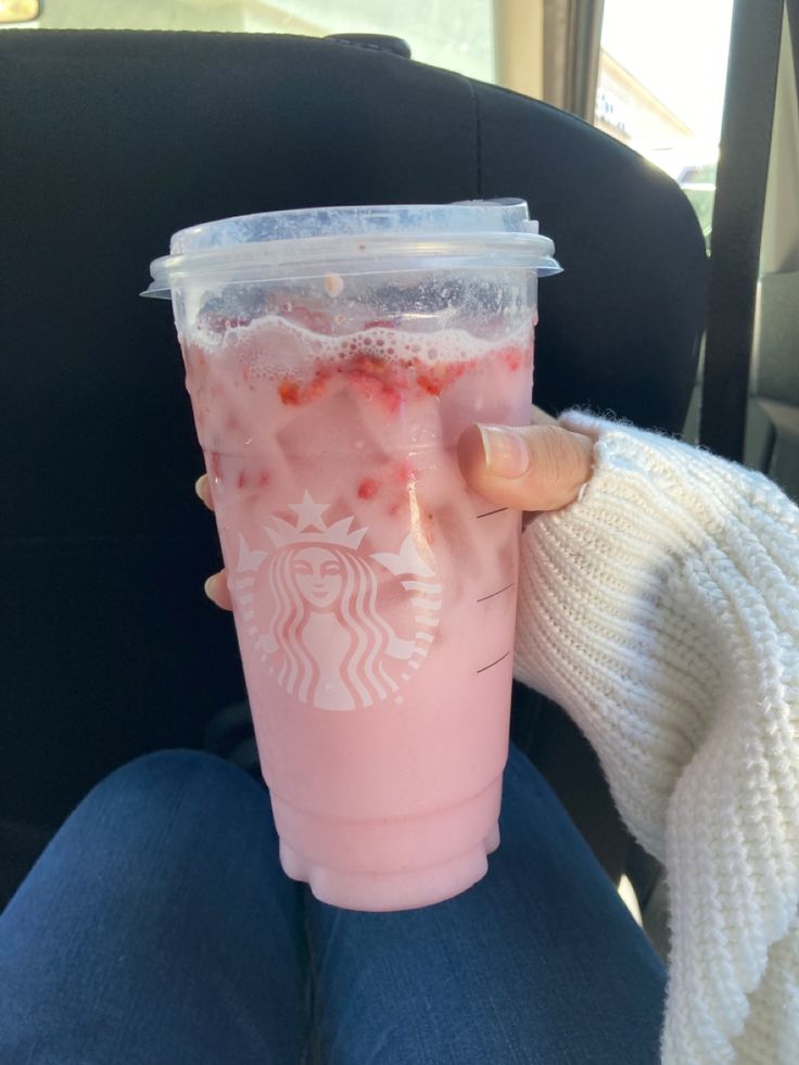 a person holding a pink drink in their hand