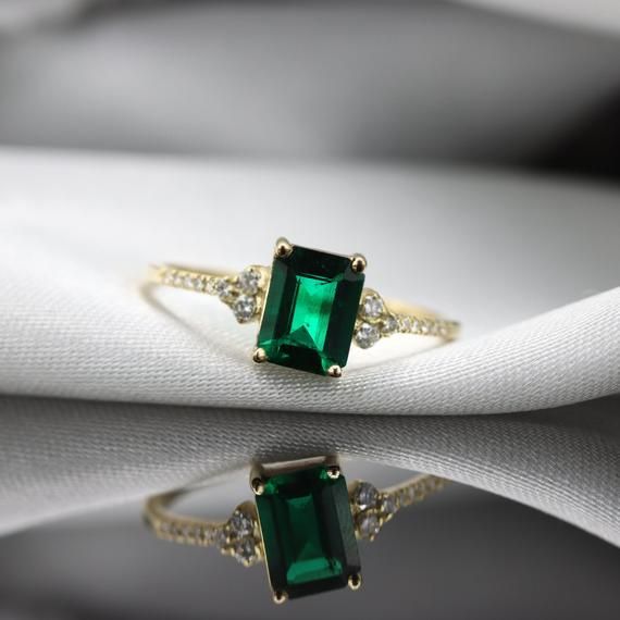 Handmade by an inspired jewelry artist team with decades of experience in the craft of jewelry making.Each gemstone, each diamond is carefully picked.Using only the finest raw materials and the highest industry standard in manufacturing, design and finish.A beautiful vintage inspired piece handmade just for you.An impressive radiant cut emerald brings rich color to this ring, contrasted by brilliant diamond side stones set in a shimmering 10,14 or 18 Karat gold setting.Ring Features:- Gemstone i Timeless Emerald Diamond Wedding Ring, Timeless Emerald Gemstone Wedding Ring, Timeless Emerald Anniversary Ring, Green Timeless Diamond Wedding Ring, Timeless Emerald Wedding Anniversary Ring, Timeless Green Wedding Rings For Anniversary, Classic Emerald Promise Ring With Birthstone, Classic Emerald Diamond Promise Ring, Classic Emerald Diamond Ring With Accent Stones