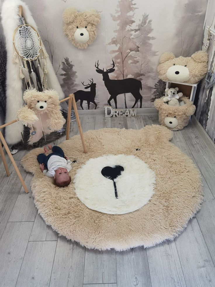 there is a baby laying on the floor in front of stuffed bears and deers