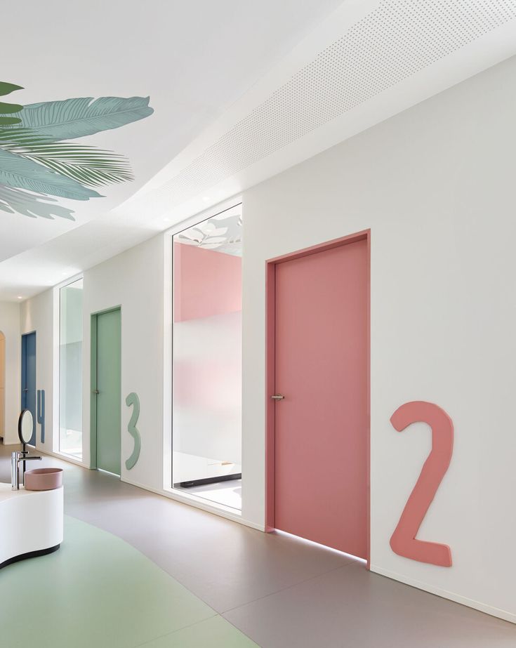 the interior of a modern home with pink door and green plant on the wall next to it