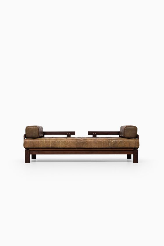 a brown leather couch sitting on top of a white floor next to a wooden frame