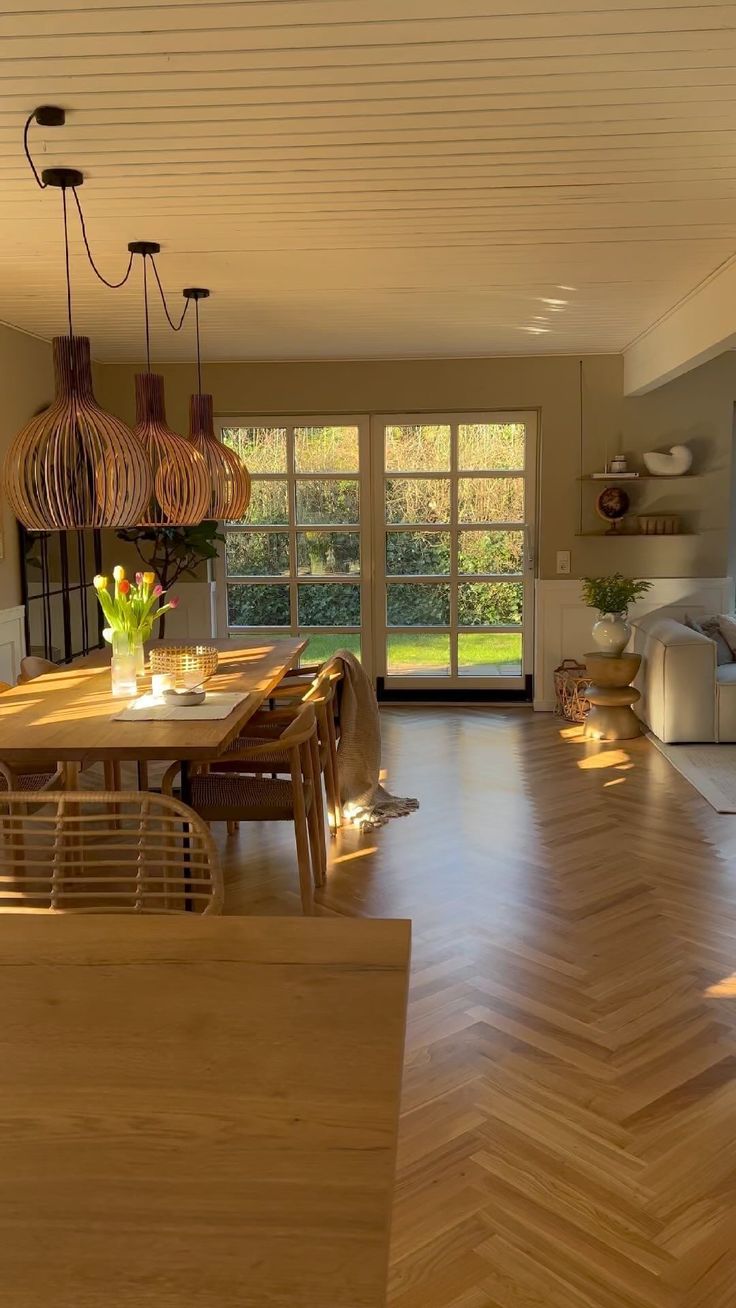 an open living room and dining area with wood flooring, large windows in the background