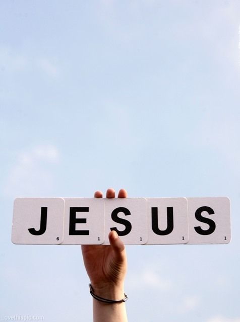 a person holding up a sign with the word jesus on it in front of a blue sky