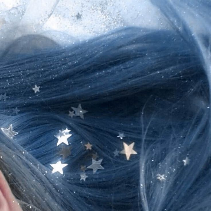 a woman with blue hair and silver stars on her head