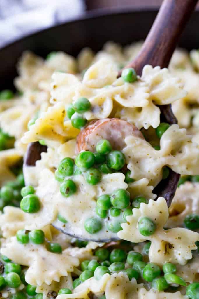 a bowl filled with pasta and peas on top of a wooden spoon in the middle