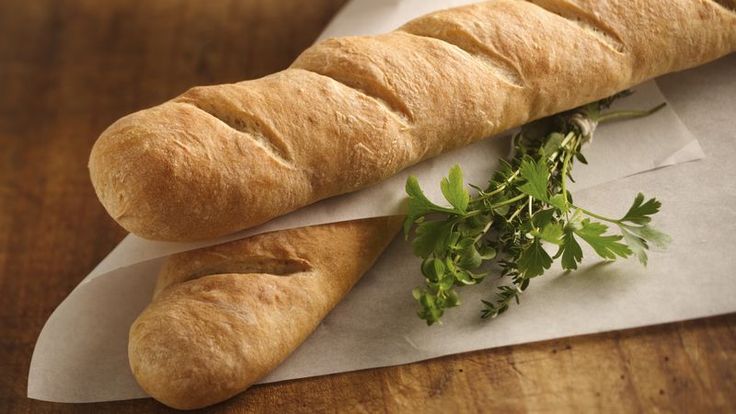 two loaves of bread sitting on top of a piece of paper next to a sprig of parsley