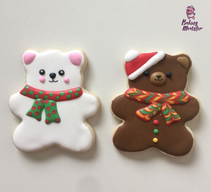 two decorated cookies sitting next to each other on a white counter top in the shape of teddy bears