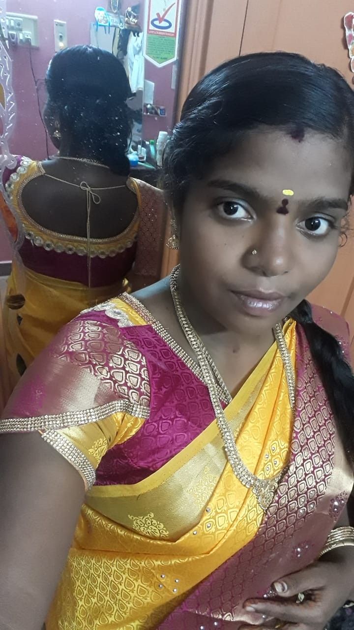 a woman in a yellow and pink sari looking at the camera with her hands on her hips