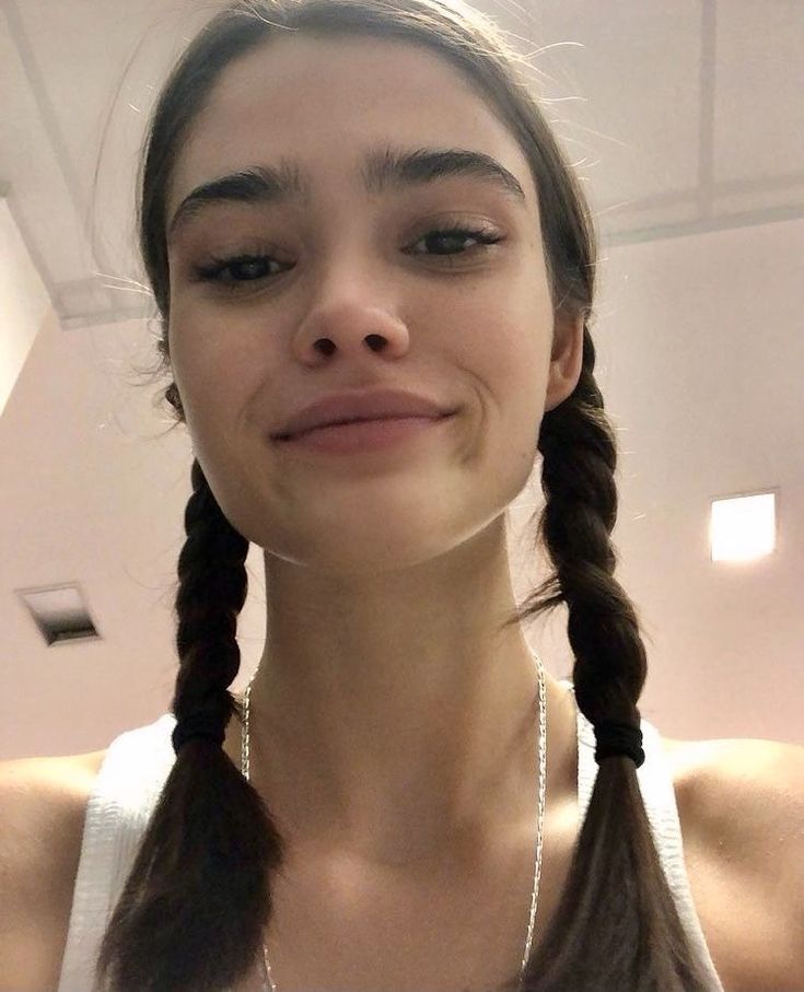 a woman with braids and a necklace on her neck looking up at the camera