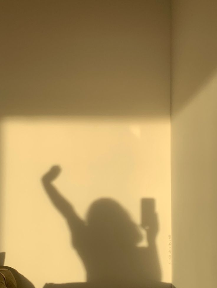 the shadow of a person sitting on a couch holding a remote control in their hand