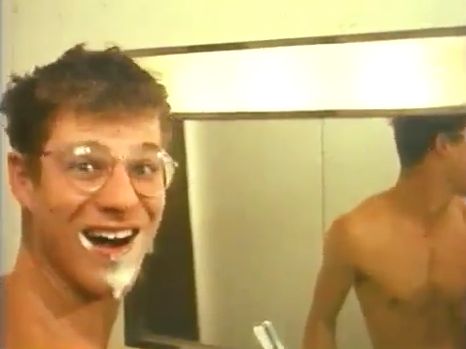 a shirtless man is brushing his teeth in the mirror