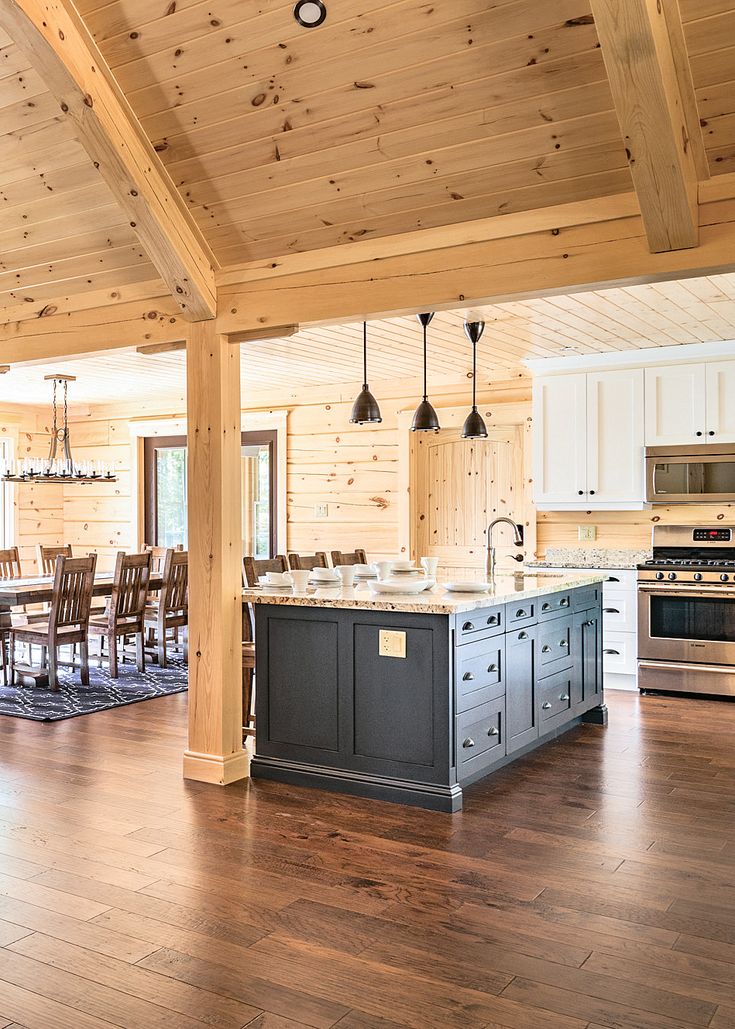 an open kitchen and dining room with wood flooring in a log cabin style home