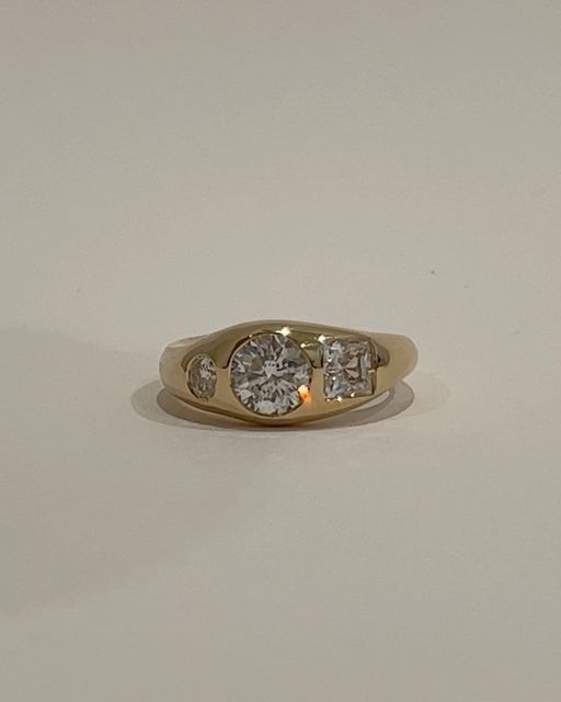 a three stone diamond ring on a white surface