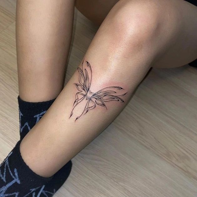 a woman is sitting on the floor with her legs crossed, and she has a flower tattoo on her left leg