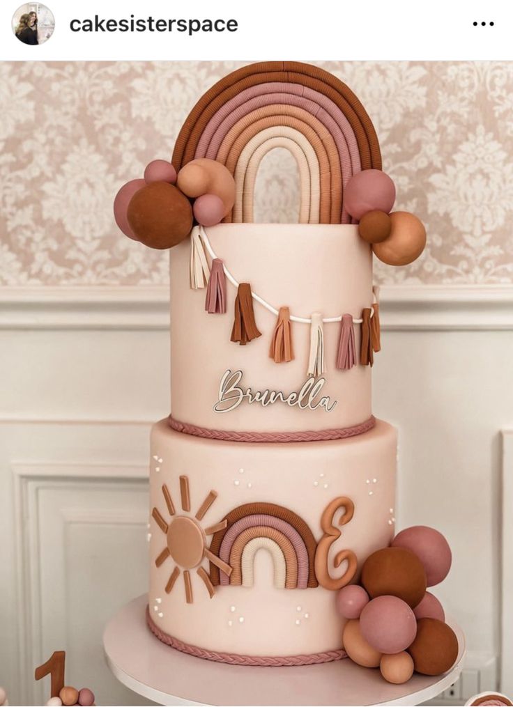 a three tiered cake decorated with rainbows and tassels