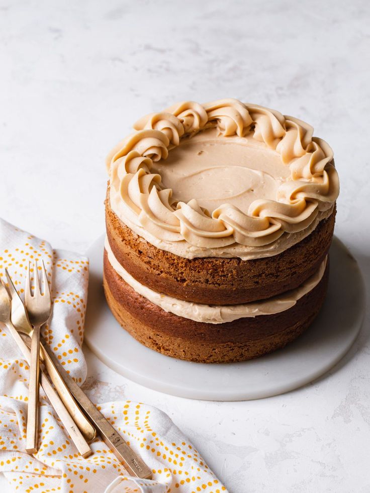 a cake with frosting on a plate next to two forks and napkins in front of it