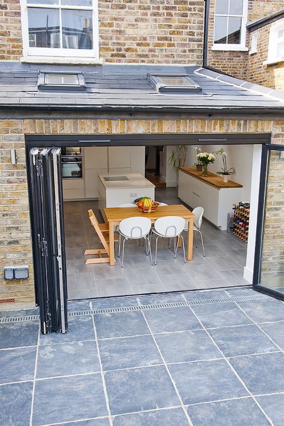 an open garage door with a table and chairs in the center, on a patio