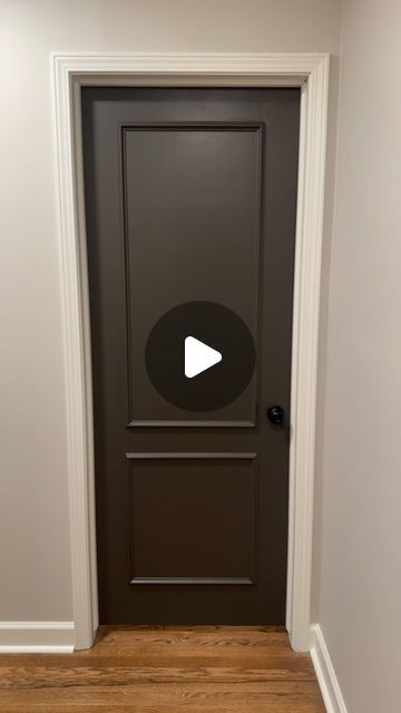 a door with a play button on it in a room that has wood floors and white walls