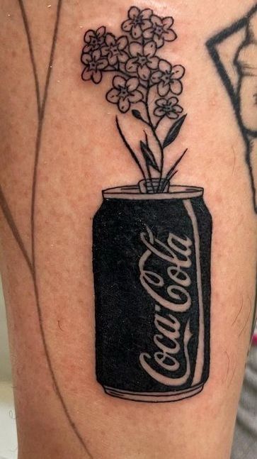 a black and white photo of a flower in a can tattoo on the leg,