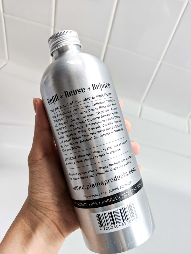 a hand holding a bottle of light house alumium in front of a white tiled ceiling