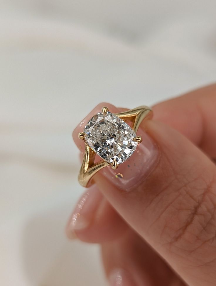 a woman's hand holding an engagement ring with a diamond in the center, on top of her finger