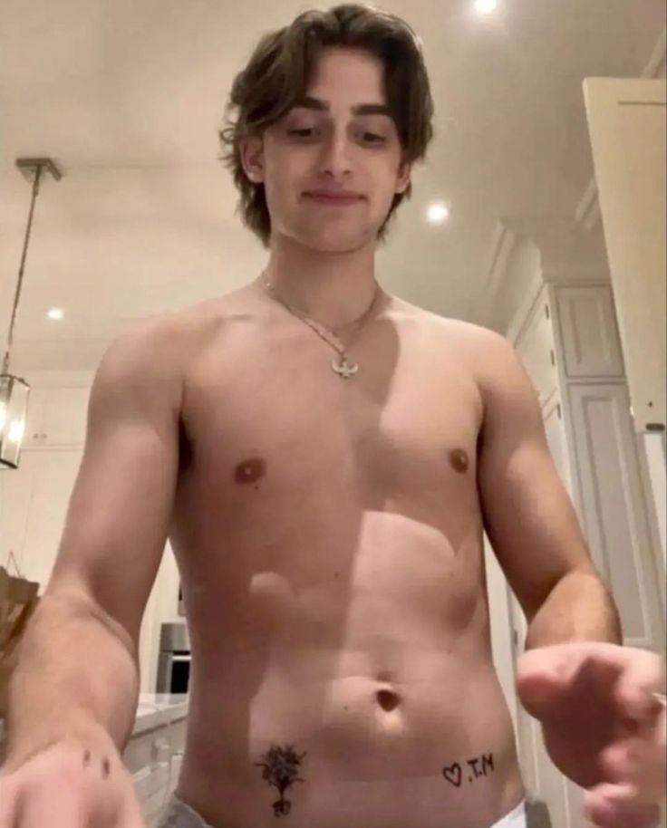 a shirtless young man with no shirt on in the kitchen holding his hands out