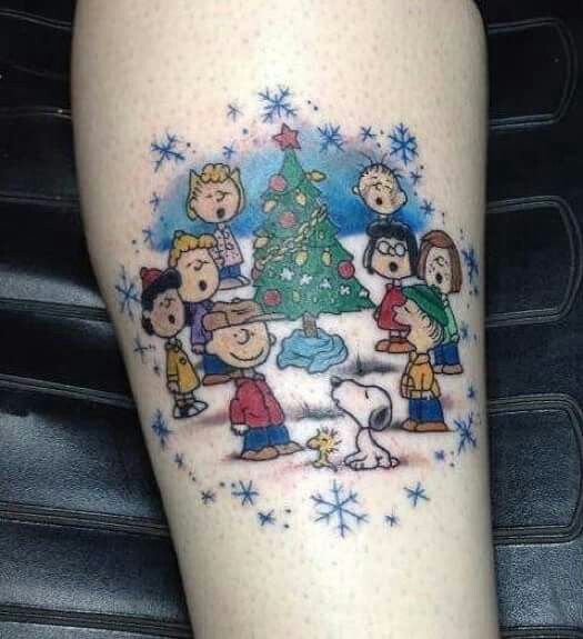 a person with a christmas tree tattoo on their leg and the image of peanuts around it