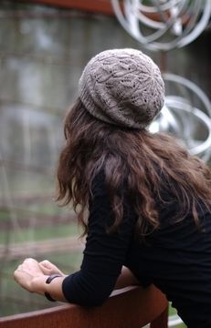 a woman with long hair wearing a hat looking out over a fence at an animal exhibit