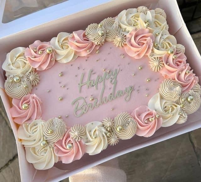 a pink and white birthday cake in a box with the words happy birthday written on it