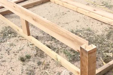 a wooden bed frame sitting in the dirt