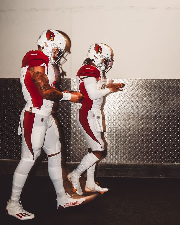 two football players in white and red uniforms standing next to each other with their hands together