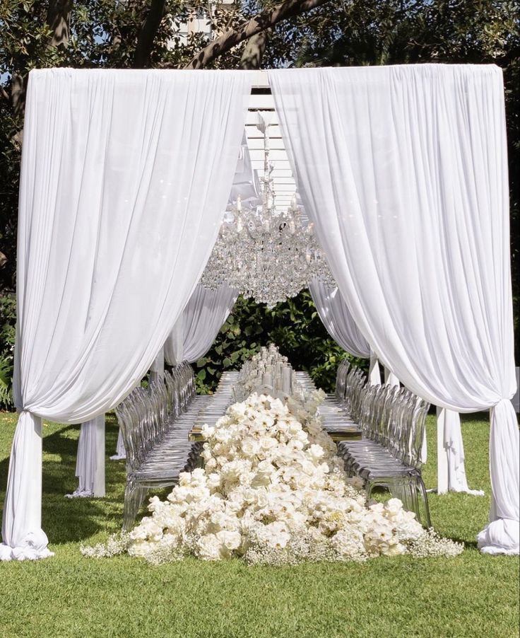 an outdoor wedding setup with white drapes and flowers