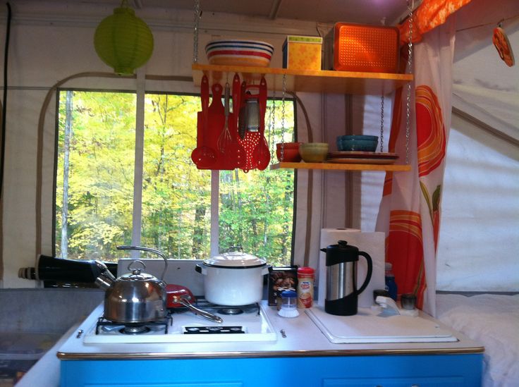 a kitchen area with pots and pans hanging from the ceiling next to an open window