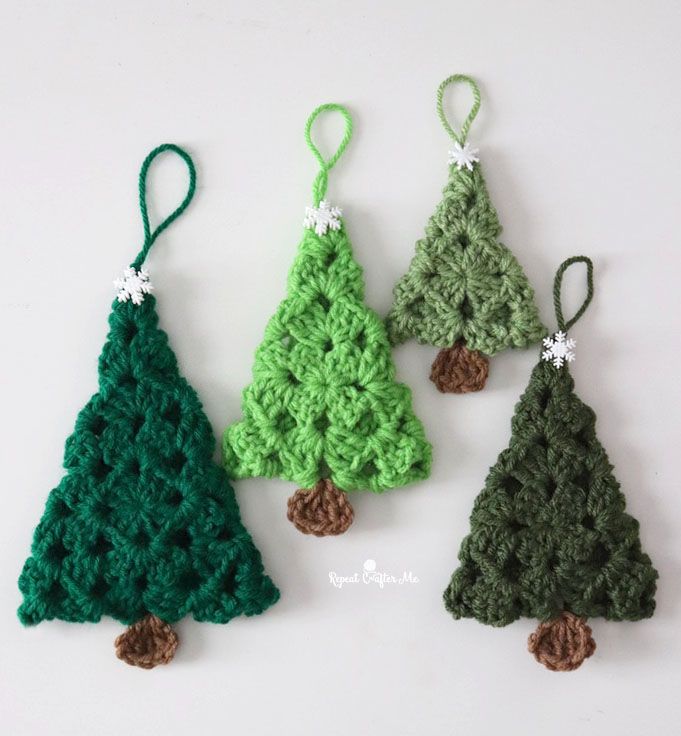 three crocheted christmas trees hanging from green string