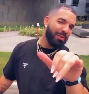 a man in a black shirt is pointing to the side with his finger and wearing a gold chain