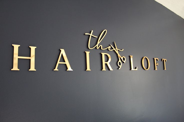 there is a sign that says this hair loft in gold letters on the wall above it