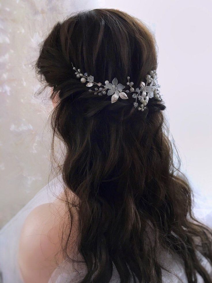 a woman wearing a bridal hair comb with flowers on it's head and long dark hair