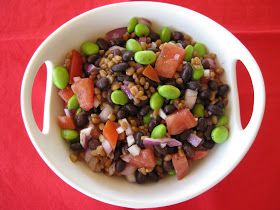 a white bowl filled with beans and veggies on top of a red table