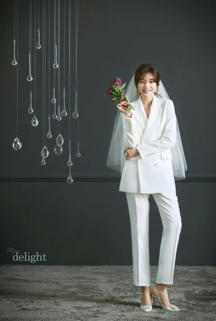 a woman in a white suit holding a flower