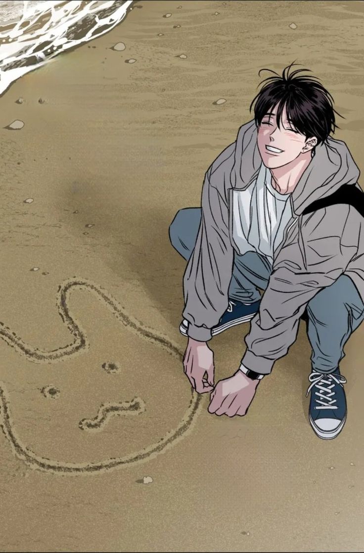 a man kneeling down on top of a sandy beach next to the ocean and writing in the sand