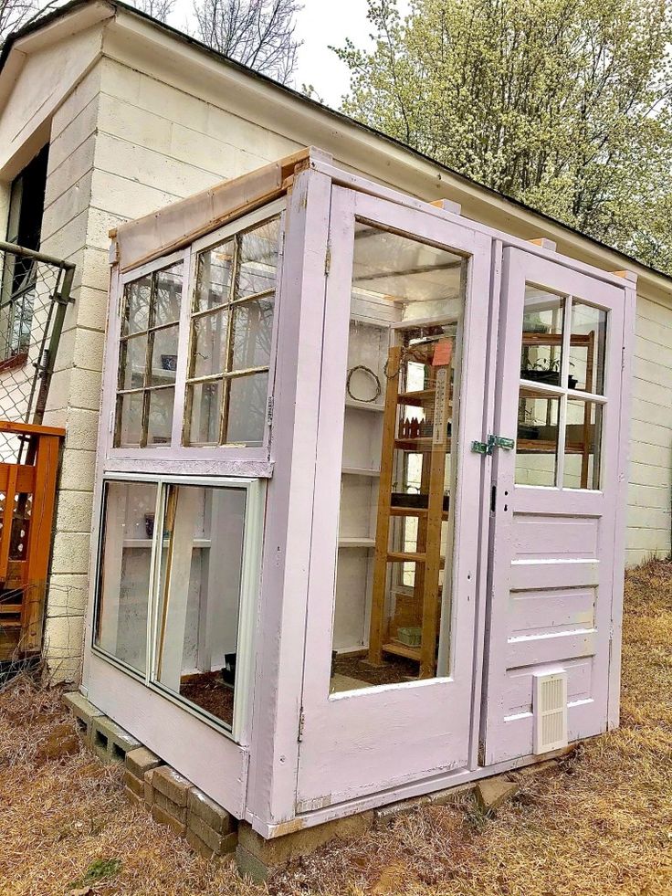 an old outhouse is painted purple and has glass doors on the front, windows in the back