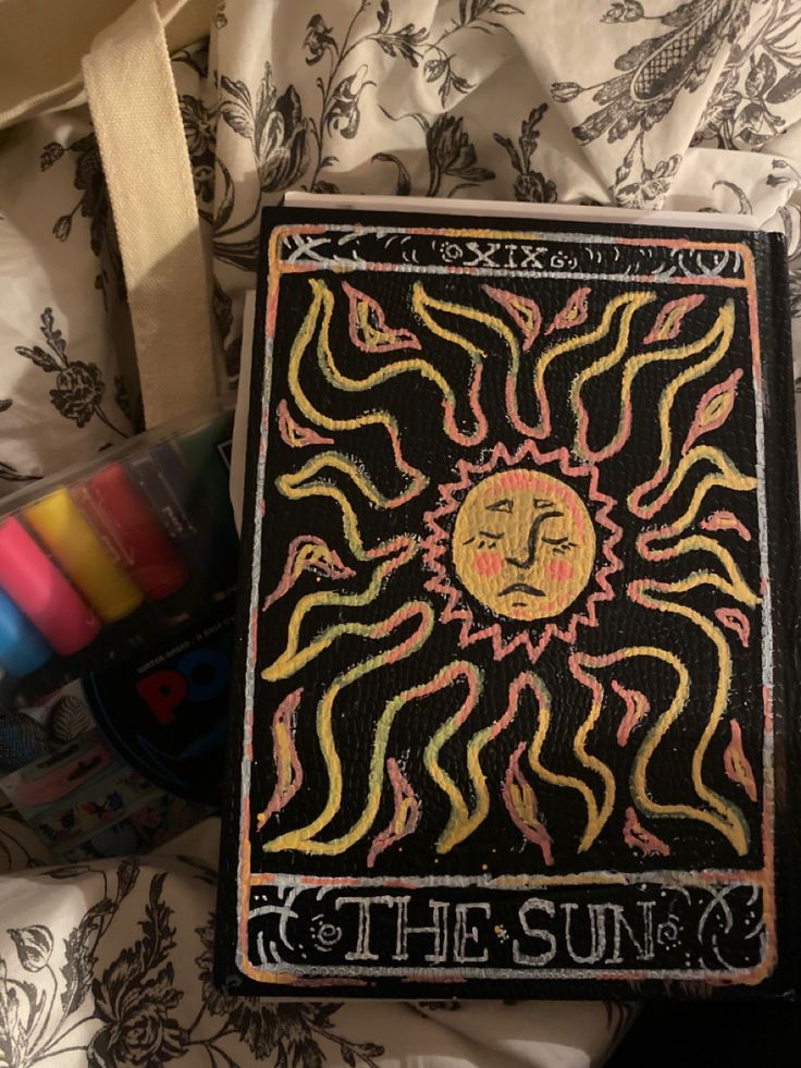 the sun is drawn on top of a book with crayons next to it