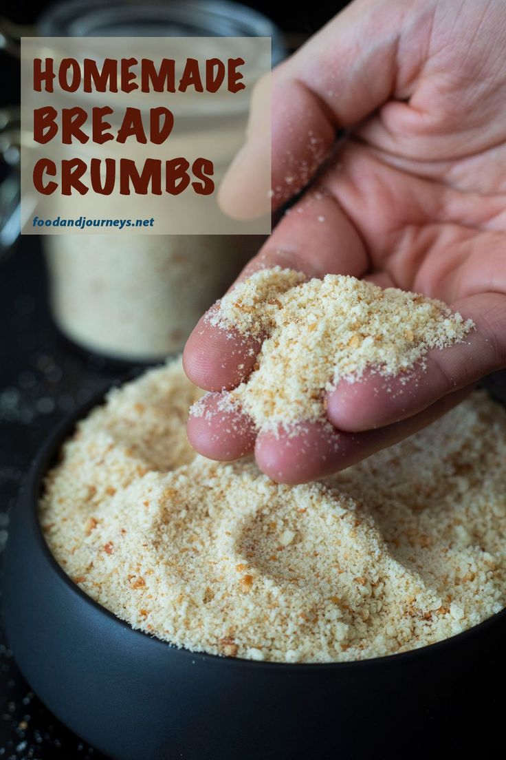 a hand is scooping out some bread crumbs from a black bowl on a counter