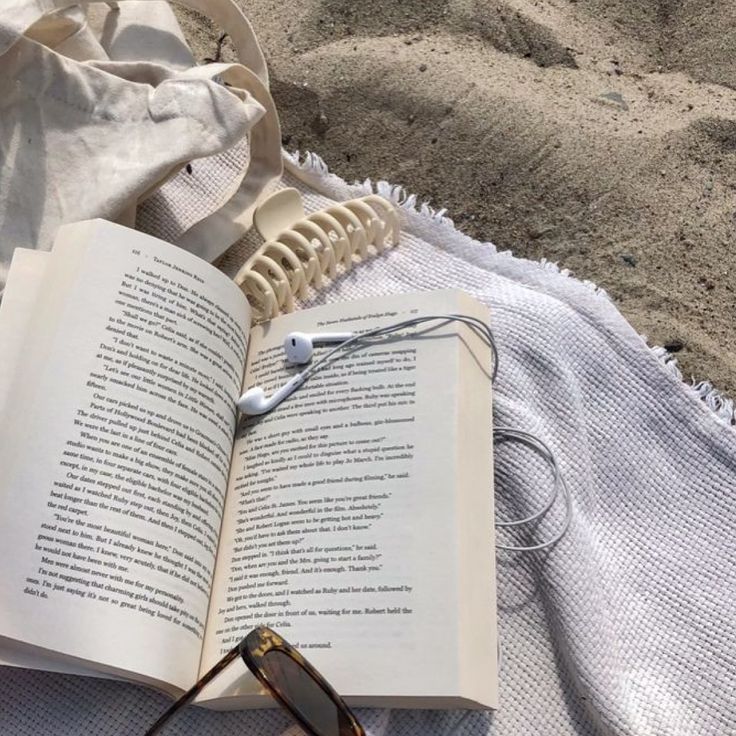 an open book with headphones on top of it next to a pair of glasses