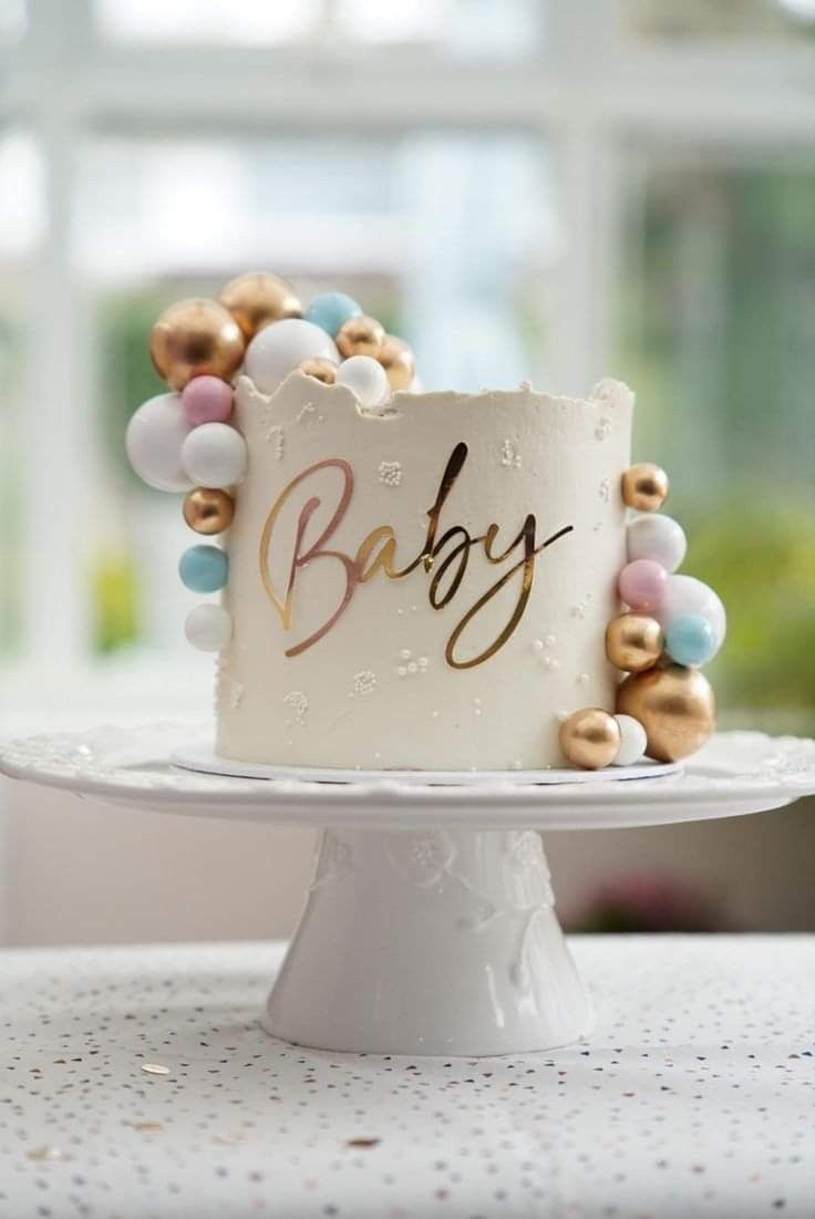 a white cake with gold and blue decorations on it's top that says baby