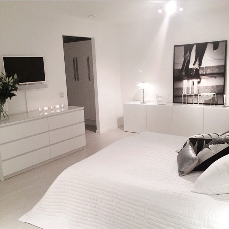 a white bed sitting in a bedroom next to a tv